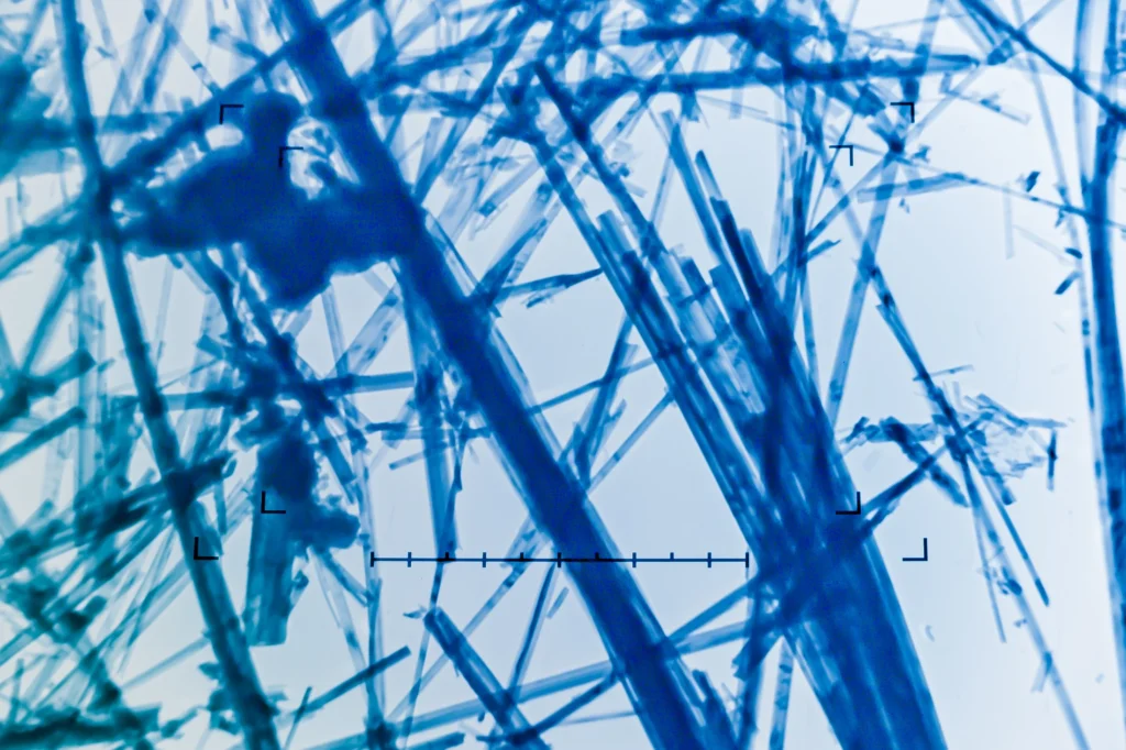 Magnified blue asbestos fibres viewed through laboratory microscopy.