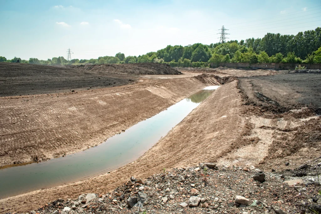 Prepared ground and a water channel at a former industrial site undergoing remediation.