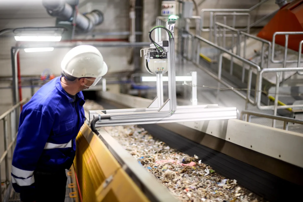 An operator inspecting materials moving along a waste processing line.