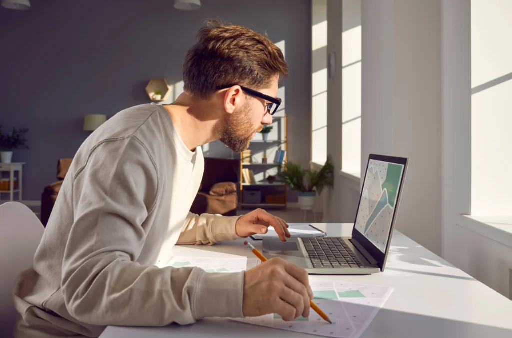 A researcher comparing paper maps with mapping information on a laptop.