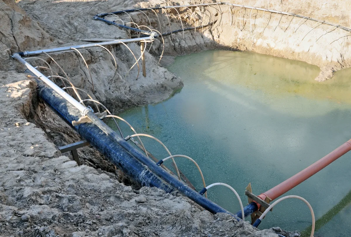 Groundwater pumping pipes arranged around a water-filled excavation.